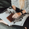 A woman sitting on the couch looking at an open book.