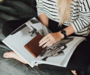 A woman sitting on the couch looking at an open book.