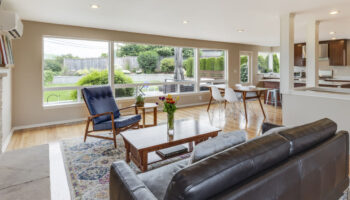 A living room with a couch, chairs and table.