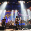 A band performing on stage with lights in the background.