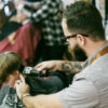 A man with a beard and glasses is looking at his camera.