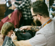 A man with a beard and glasses is looking at his camera.