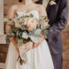 A bride and groom holding their wedding bouquet.