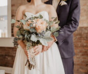 A bride and groom holding their wedding bouquet.