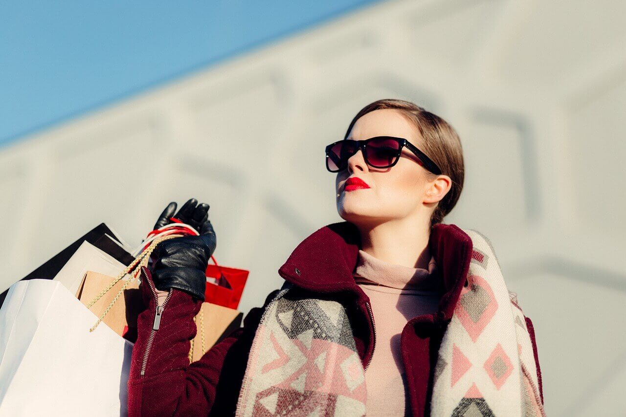 A woman in sunglasses holding onto some bags