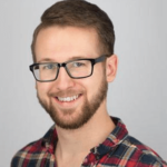 A man with glasses and beard wearing a plaid shirt.