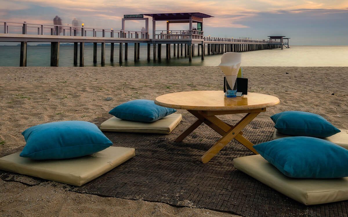 A table and chairs on the beach near water