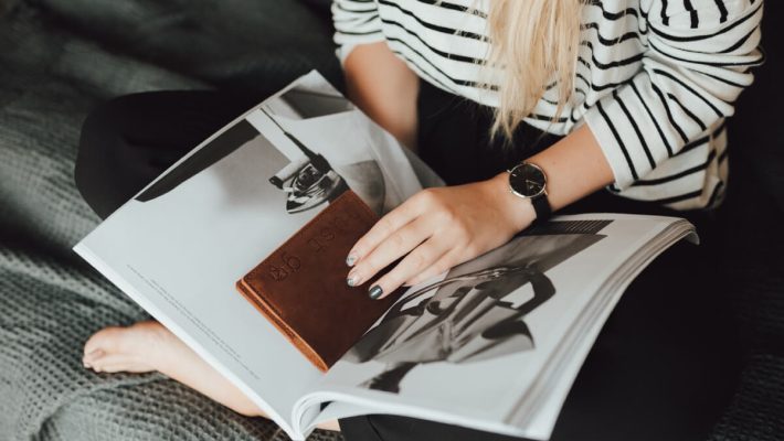 A woman sitting on the couch looking at an open book.
