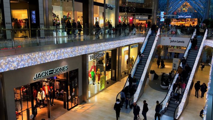 A group of people walking around an indoor mall.