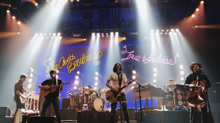 A band performing on stage with lights in the background.