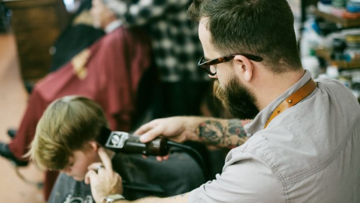 A man with a beard and glasses is looking at his camera.