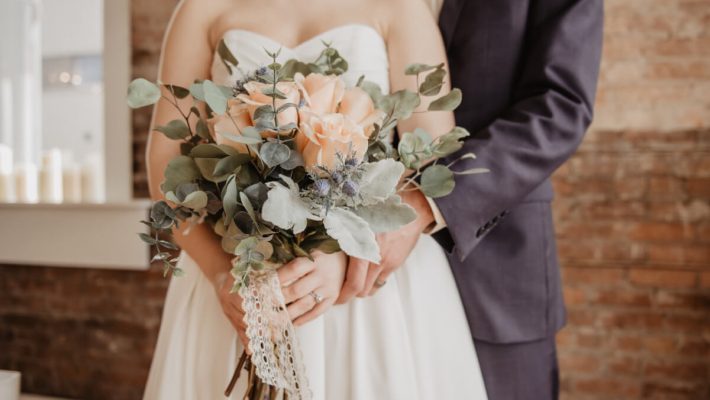 A bride and groom holding their wedding bouquet.