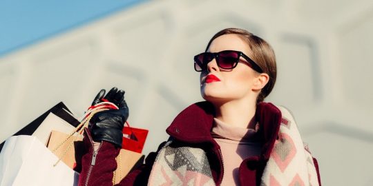 A woman in sunglasses holding onto some bags